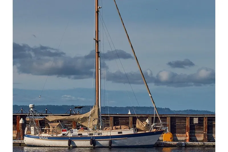 Slide: The Image of 1983 Valiant 40 Selah sailboat docked with sails down, under a cloudy sky. - 113