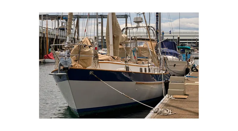 Slide: The Image of 1983 Valiant 40 Selah sailboat docked at marina, covered sails, calm water. - 2