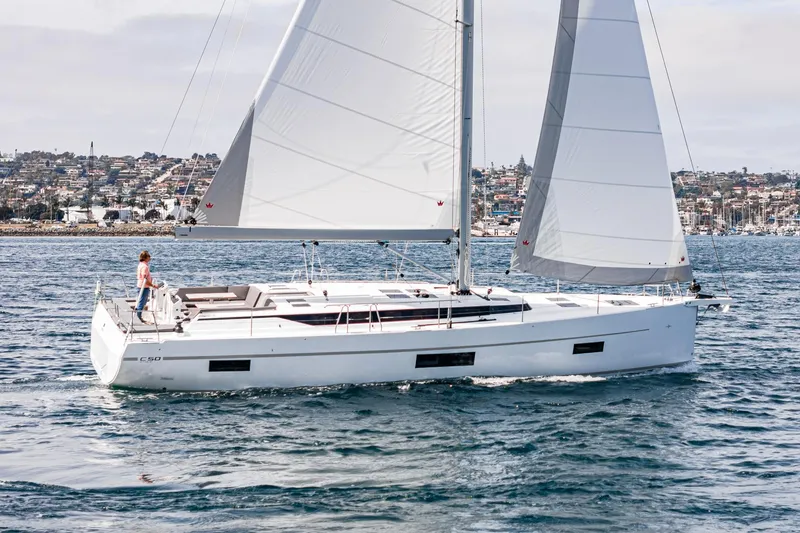 Slide: The Image of 2024 Bavaria C50 sailboat cruising on open water near a coastal city. - 8