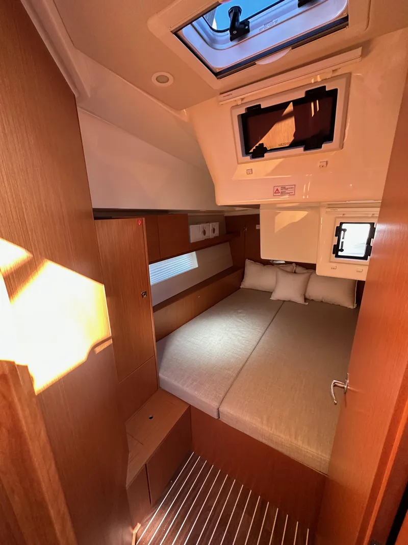 Slide: The Image of 2024 Bavaria C45 yacht cabin interior with bed, skylight, and wooden finishes. - 46