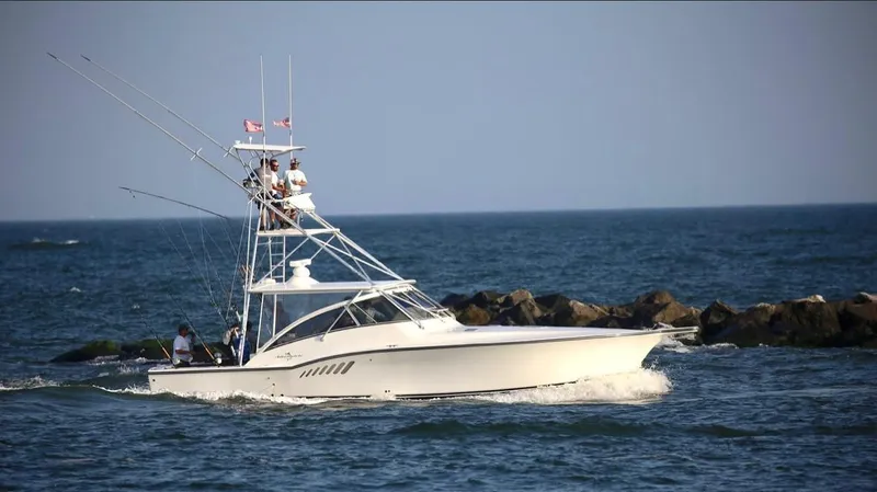 Slide: The Image of 2002 Albemarle 410 Express Fisherman boat cruising near rocky shoreline. - 0