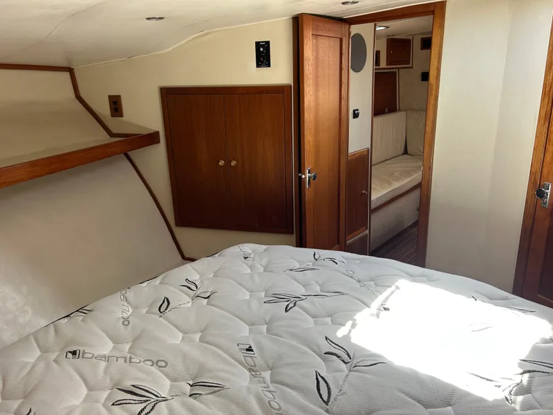 Slide: The Image of 2002 Albemarle 410 Express Fisherman cabin with bed, wooden cabinets, and doorway to seating area. - 30