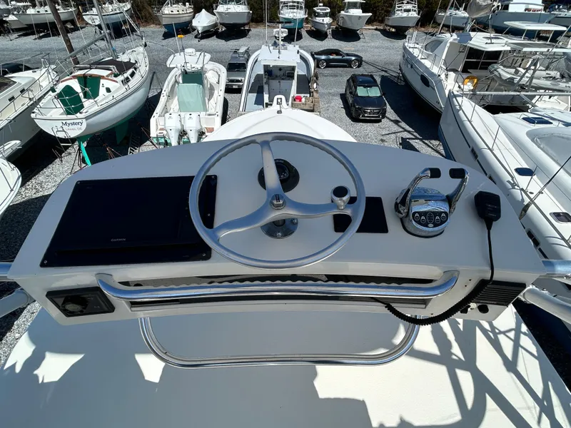 Slide: The Image of 2002 Albemarle 410 Express Fisherman helm with steering wheel and controls, surrounded by boats. - 43