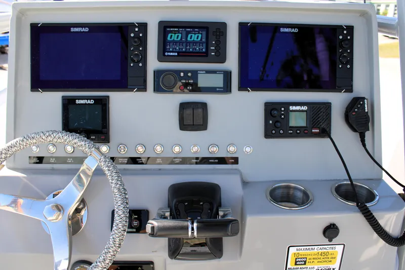 Slide: The Image of Boat dashboard with Simrad electronics, steering wheel, and controls on a 2020 Release 240 RX. - 14