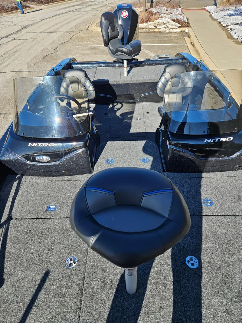 Slide: The Image of 2025 Nitro ZV19 boat interior with dual windshields and seating, parked on a sunny day. - 2