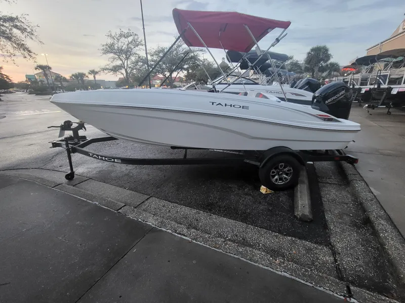 Slide: The Image of 2025 Tahoe T18 boat on trailer, parked outdoors, with a red canopy. - 0