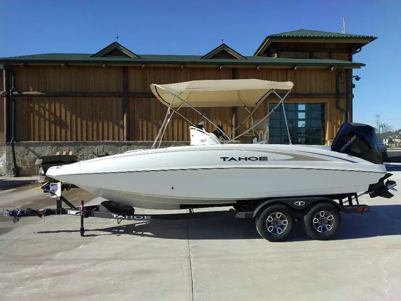 Slide: The Image of 2025 Tahoe 2150 CC boat on trailer, parked outdoors with building background. - 0