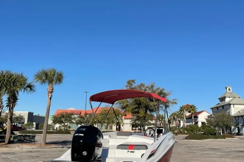 Slide: The Image of 2025 Tahoe T16 boat with red canopy in a sunny parking lot. - 3