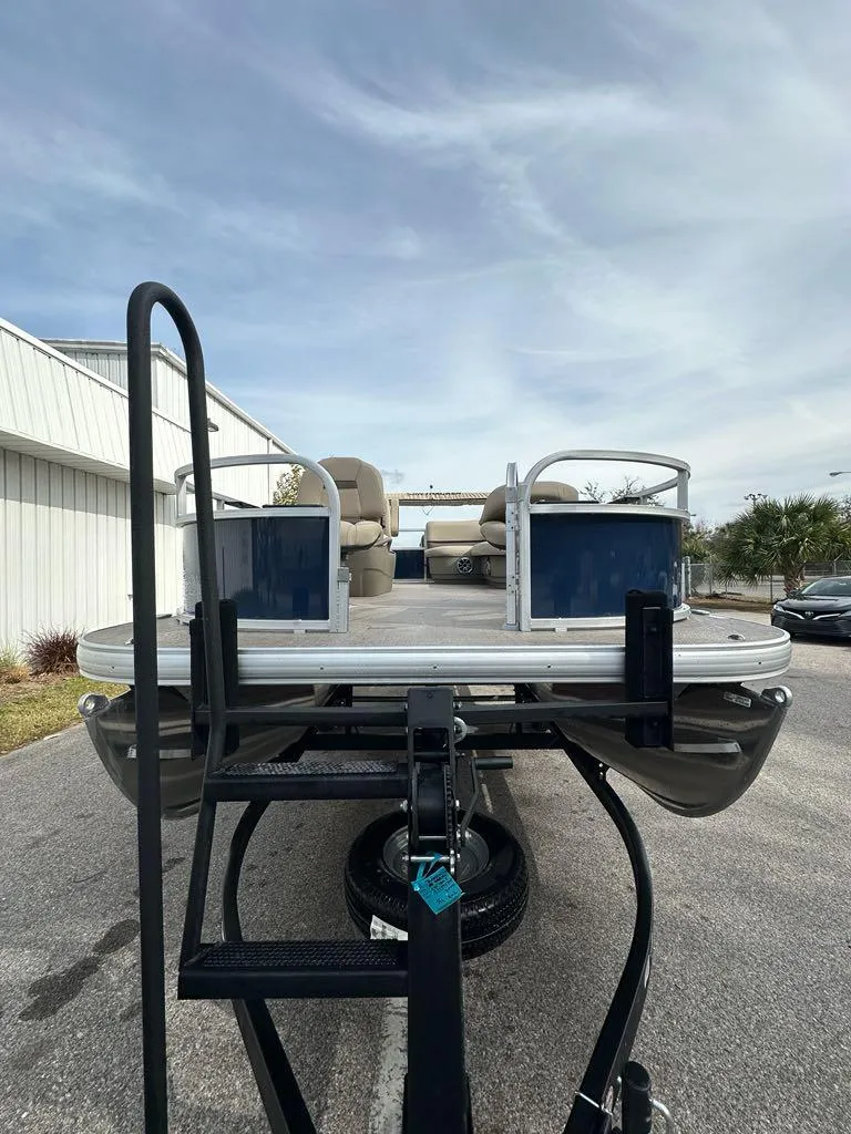 Slide: The Image of 2025 Sun Tracker Bass Buggy 16 XL Select pontoon boat on trailer, outdoor setting. - 11