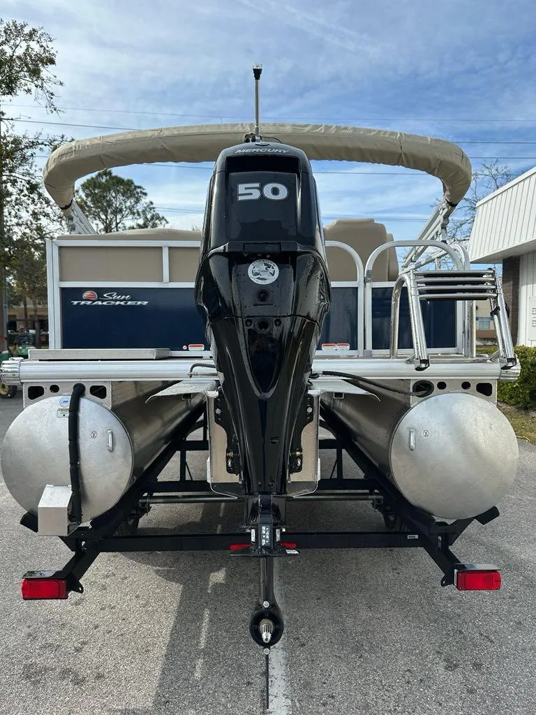 Slide: The Image of 2025 Sun Tracker Bass Buggy 16 XL Select pontoon boat with 50 HP engine, parked outdoors. - 5