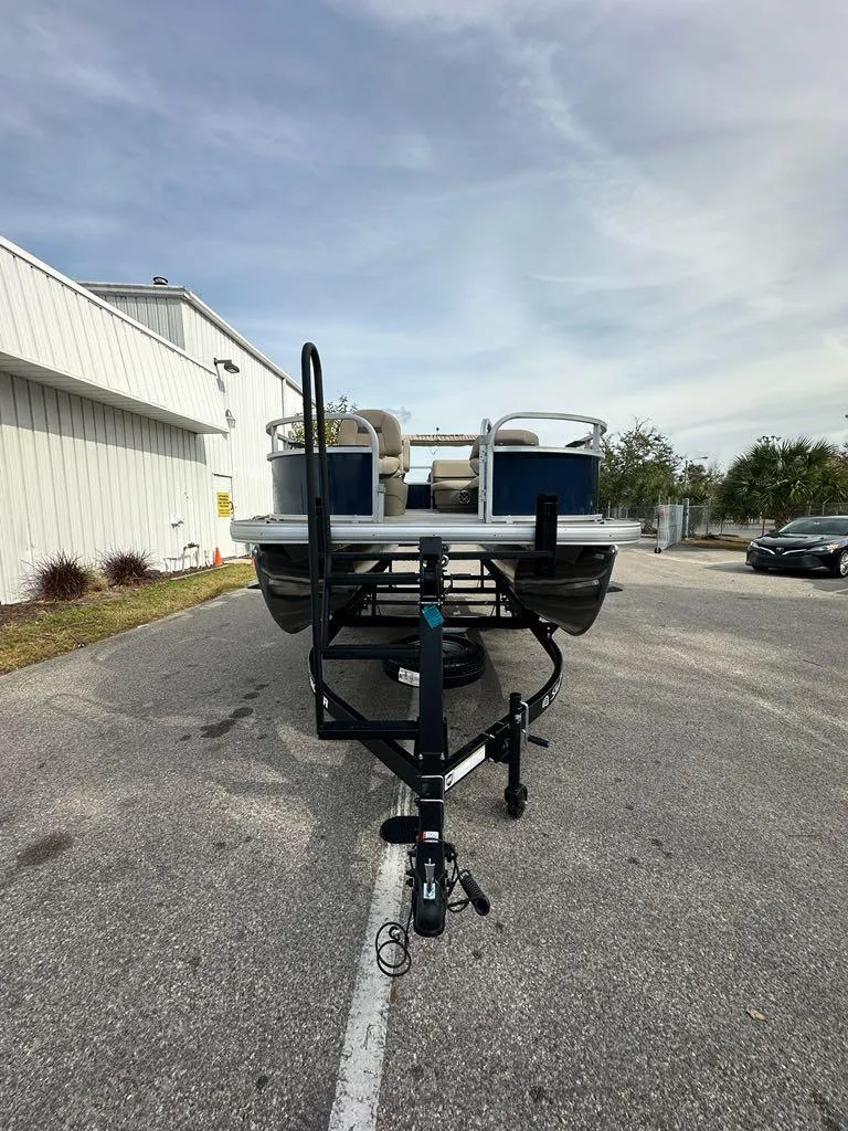Slide: The Image of 2025 Sun Tracker Bass Buggy 16 XL Select pontoon boat on trailer, parked outdoors. - 9