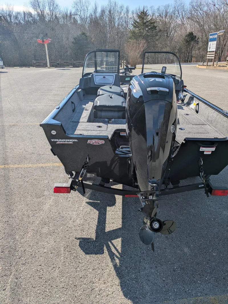 Slide: The Image of 2025 Tracker Pro Guide V-16 WT boat with outboard motor in parking lot. - 6