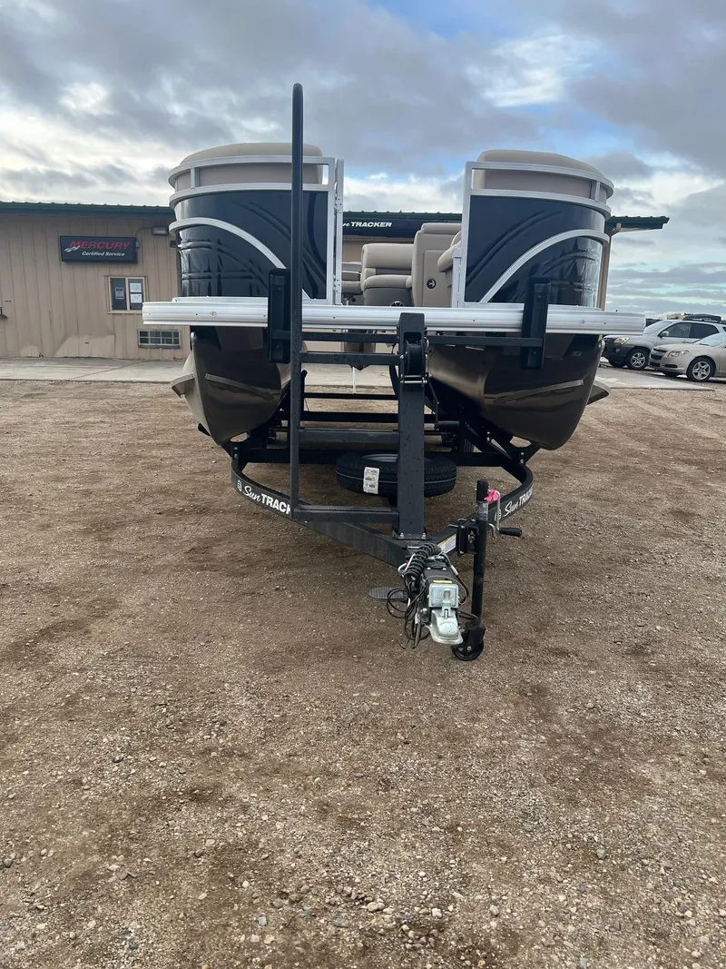 Slide: The Image of 2025 Sun Tracker SportFish 22 DLX pontoon boat on trailer, parked outdoors. - 2