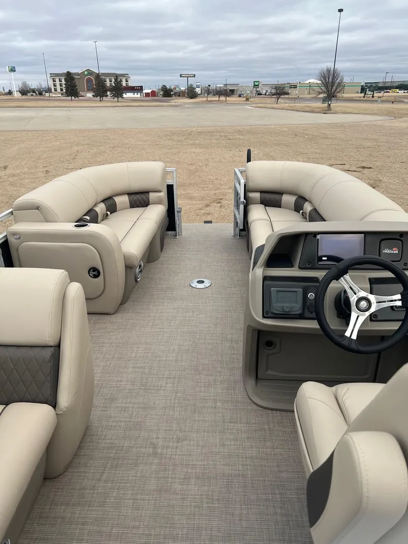 Slide: The Image of 2025 Sun Tracker SportFish 22 DLX pontoon boat interior with beige seating and steering console. - 5