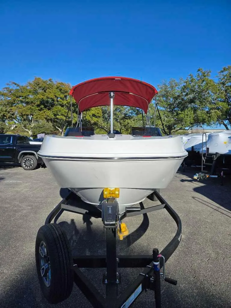 Slide: The Image of 2025 Tahoe T21 boat with red canopy on trailer, parked outdoors. - 4