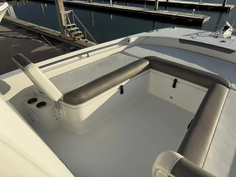 Slide: The Image of 2022 World Cat 235 CC boat interior with cushioned seating and cup holders at a marina. - 10