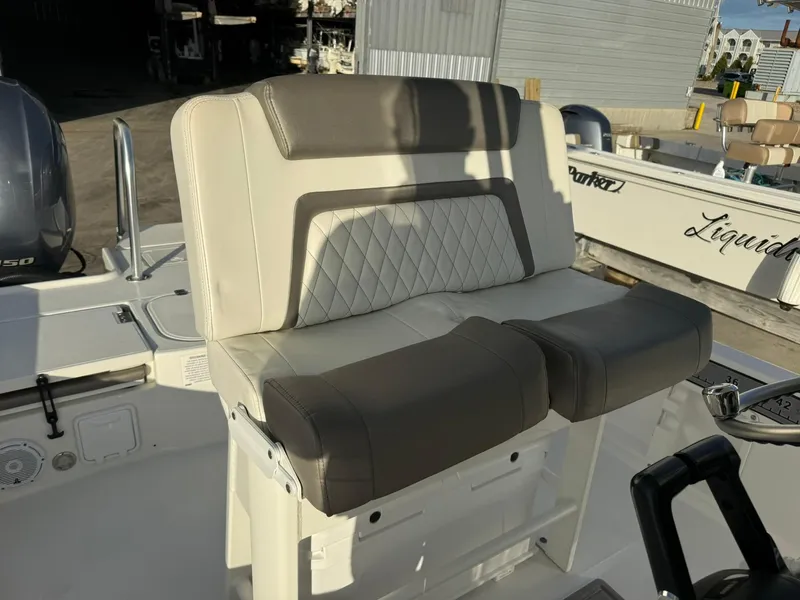 Slide: The Image of 2022 World Cat 235 CC boat seat with gray and white upholstery in a marina setting. - 11