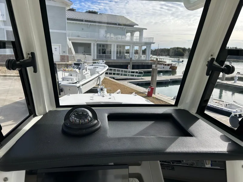 Slide: The Image of 2022 World Cat 235 CC boat dashboard with compass, docked at marina. - 18