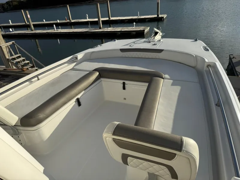 Slide: The Image of 2022 World Cat 235 CC boat interior with cushioned seating, docked by calm water. - 9