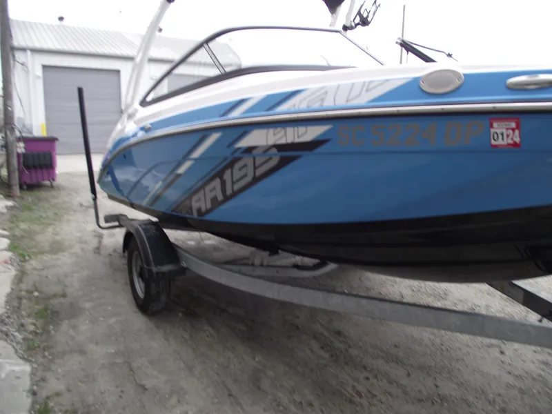 Slide: The Image of 2021 Yamaha AR195 boat on trailer, blue and white design, parked outdoors. - 2