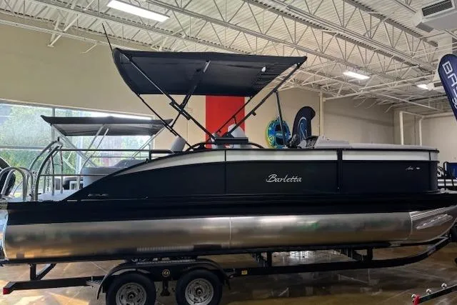 The Image of 2025 Barletta A22UC pontoon boat displayed indoors with canopy and trailer. - 0