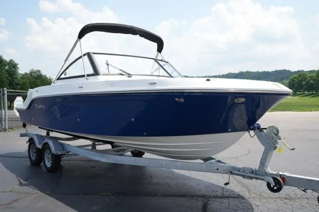 Slide: The Image of 2025 Bayliner T22SC boat on trailer, blue and white design, parked outdoors. - 2