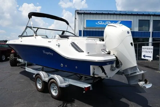 Slide: The Image of 2025 Bayliner T22SC boat on trailer outside showroom, featuring sleek blue and white design. - 4