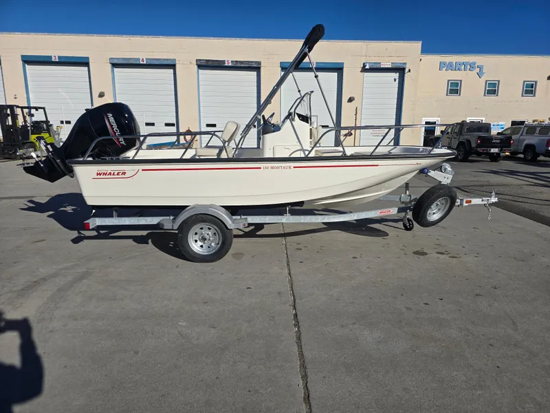 Slide: The Image of 2025 Boston Whaler 150 Montauk boat on trailer, parked outdoors. - 0