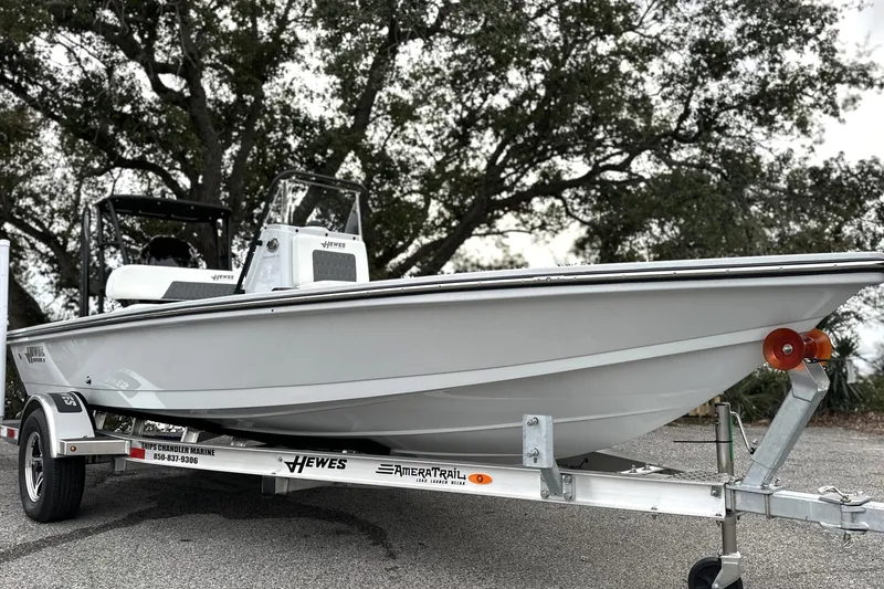 The Image of 2026 Hewes Redfisher 18 boat on trailer, parked outdoors with trees in background. - 0