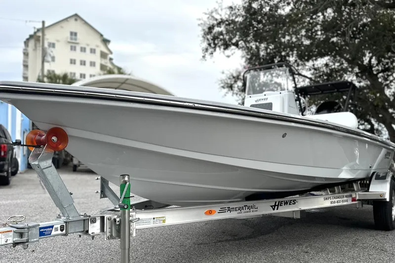 Slide: The Image of 2026 Hewes Redfisher 18 boat on trailer, parked outdoors near buildings and trees. - 12