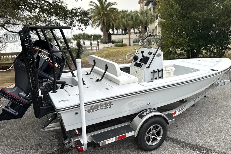 Slide: The Image of 2026 Hewes Redfisher 18 boat on trailer, parked outdoors near palm trees. - 13
