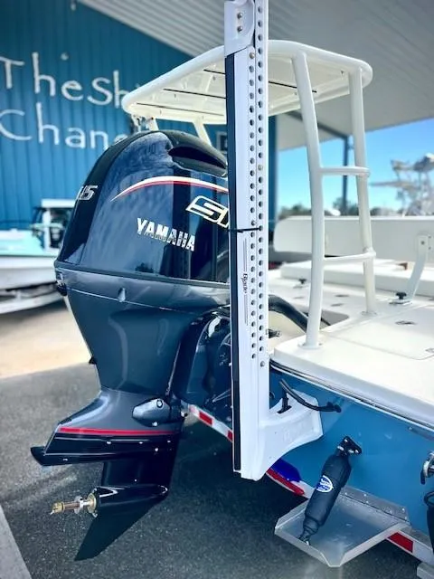 Slide: The Image of 2026 Hewes Redfisher 18 boat interior with seating and cooler, surrounded by trees. - 3