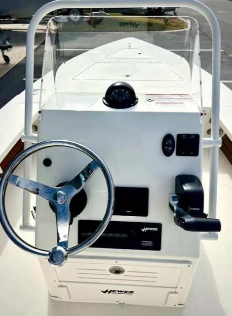 Slide: The Image of 2026 Hewes Redfisher 18 boat with seating and cooler, docked near a wooden deck. - 6