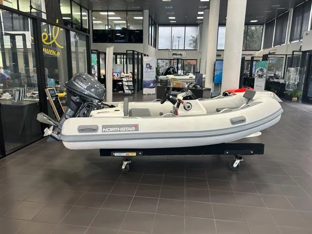 Slide: The Image of 2021 Northstar Axis 3.1 inflatable boat displayed indoors with outboard motor. - 3