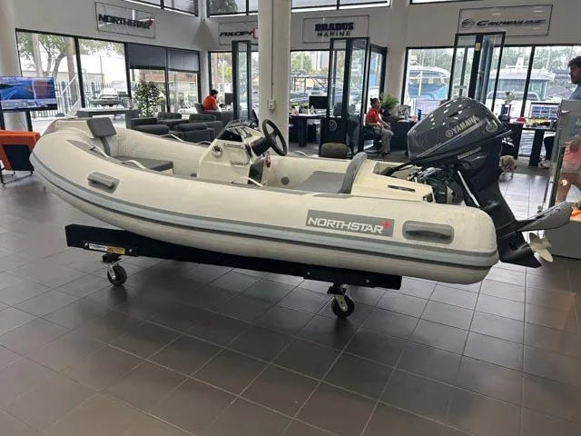 Slide: The Image of 2021 Northstar Axis 3.1 inflatable boat displayed indoors with Yamaha outboard motor. - 4
