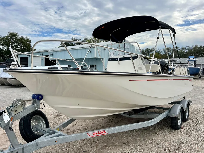 Slide: The Image of 2025 Boston Whaler 190 Montauk boat on trailer, parked outdoors under cloudy sky. - 4