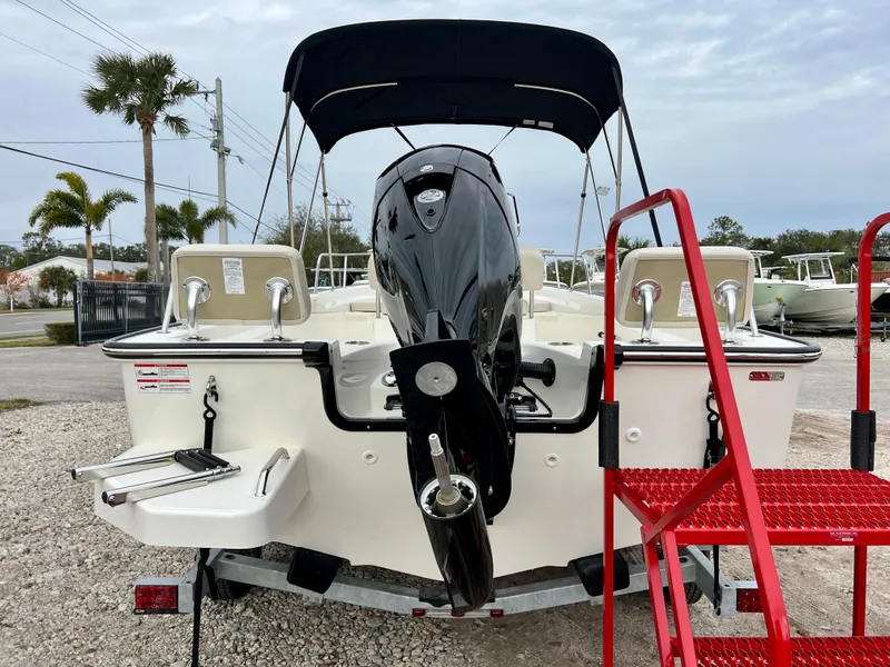 Slide: The Image of 2025 Boston Whaler 190 Montauk boat with outboard motor and canopy, parked on gravel. - 7