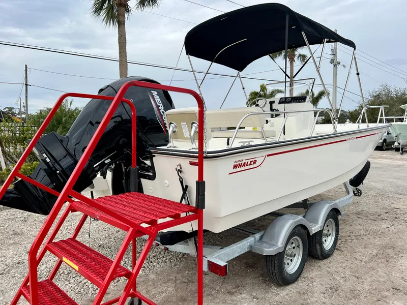 Slide: The Image of 2025 Boston Whaler 190 Montauk boat on trailer with red steps, black canopy, and outboard motor. - 8