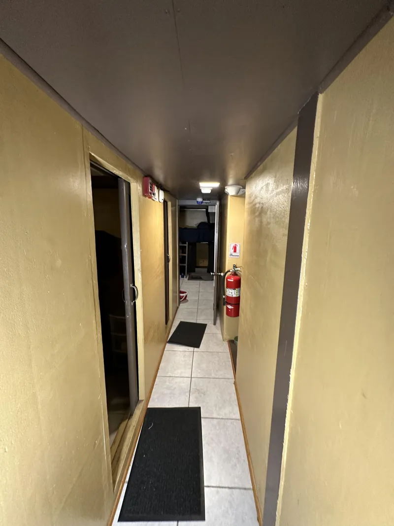 Slide: The Image of Narrow hallway inside a 1965 custom dive boat, featuring wooden walls and safety equipment. - 20