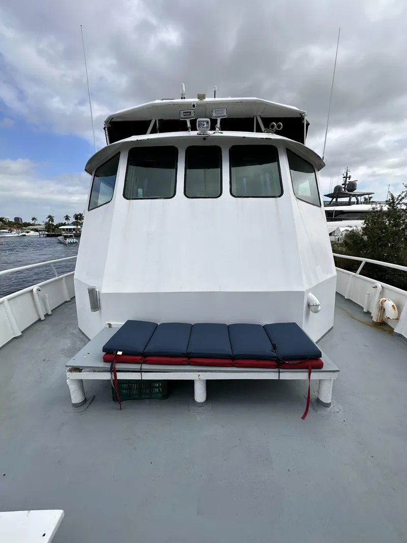 Slide: The Image of 1965 custom dive boat with cushioned seating on deck, docked under cloudy skies. - 29