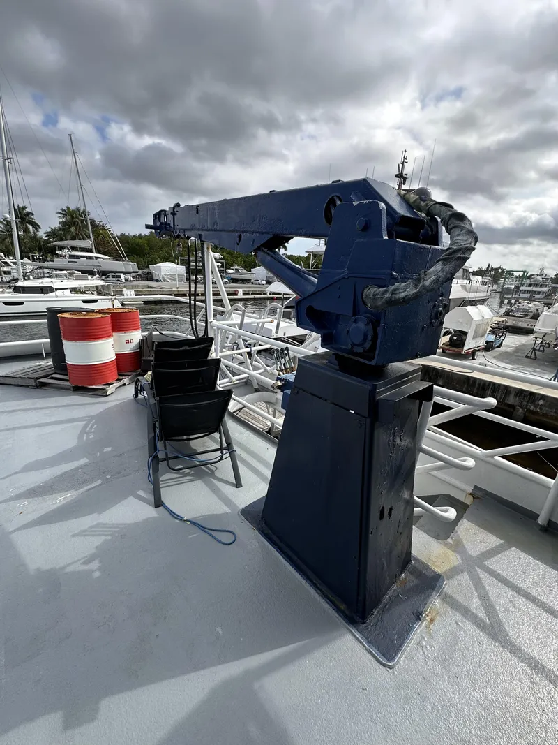 Slide: The Image of 1965 Custom Dive Boat with crane on deck, docked at marina under cloudy sky. - 48