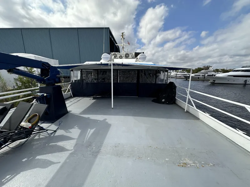 Slide: The Image of 1965 Custom Dive Boat docked, featuring spacious deck and marina backdrop under cloudy sky. - 49