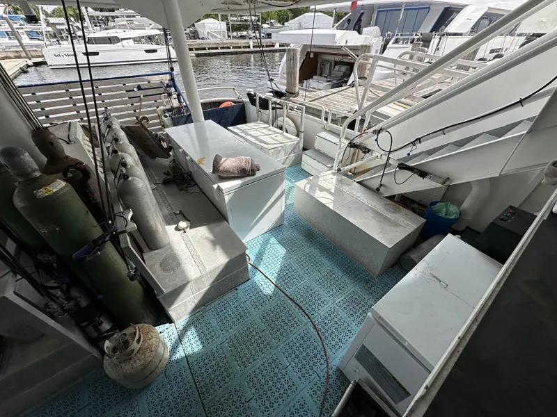 Slide: The Image of 1965 Custom Dive Boat with equipment, docked at marina, featuring blue deck flooring. - 9
