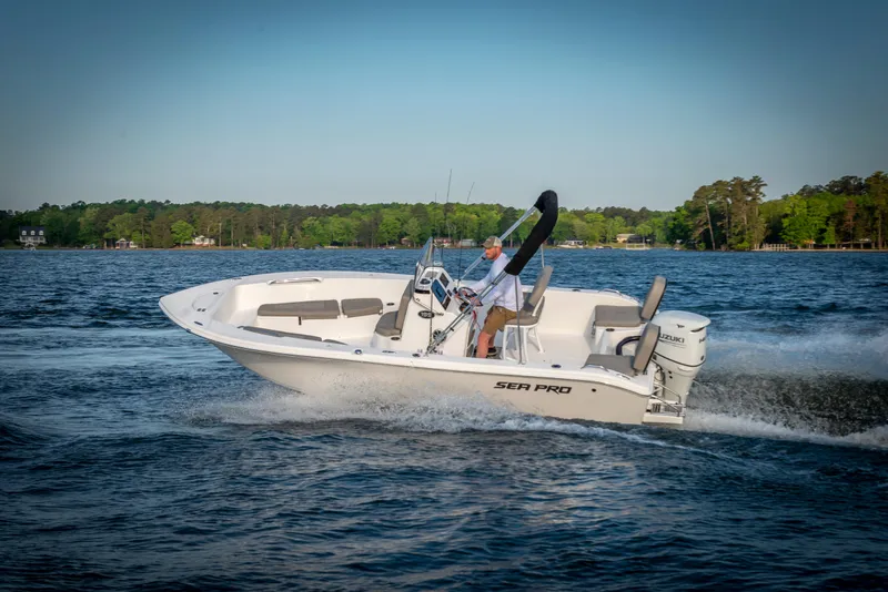 Slide: The Image of 2025 Sea Pro 202 Center Console boat cruising on a lake with lush green shoreline. - 10