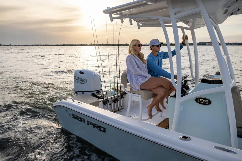 Slide: The Image of 2025 Sea Pro 202 Center Console boat cruising on water at sunset with two passengers. - 2