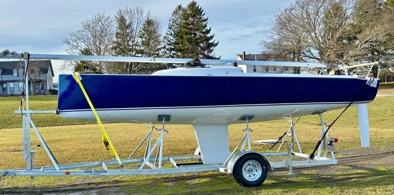 Slide: The Image of 2025 J Boats J 7 sailboat on trailer, blue hull, parked on grass. - 4