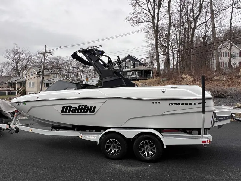 Slide: The Image of 2023 Malibu 23 LSV boat on trailer, parked near residential area. - 13
