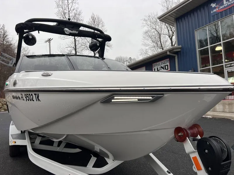 Slide: The Image of 2023 Malibu 23 LSV boat on trailer, parked near a building. - 24