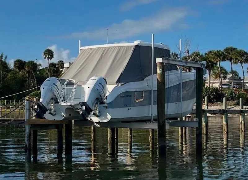 Slide: The Image of 2019 World Cat 320 DC boat on lift, docked by palm trees. - 2
