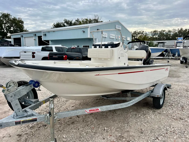 Slide: The Image of 2025 Boston Whaler 150 Montauk boat on trailer, parked outdoors near a building. - 4